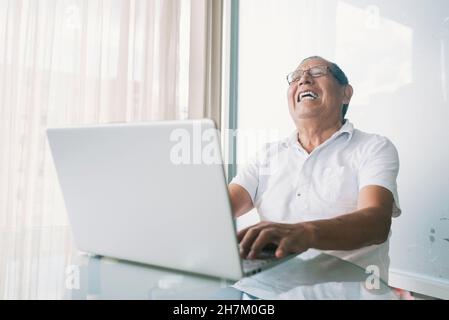 Homme d'affaires heureux avec un ordinateur portable au bureau à domicile Banque D'Images