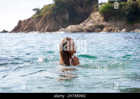 Jeune femme regardant sur l'épaule en mer Banque D'Images