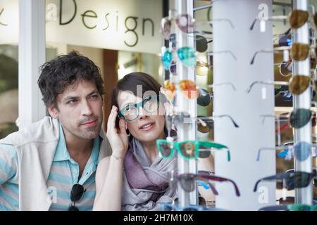 Femme essayant de lunettes par petit ami dans le magasin Banque D'Images