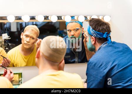 Homme barbu appliquant un fard à paupières dans un dressing Banque D'Images