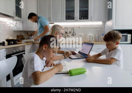 Garçon étudiant à table avec la famille en arrière-plan à la maison Banque D'Images