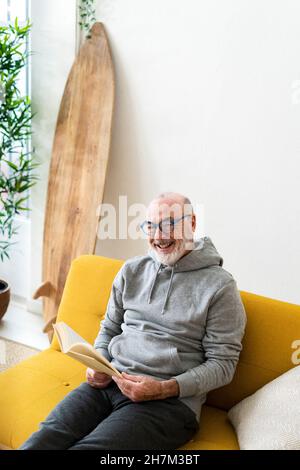 Homme de lecture senior livre dans le salon Banque D'Images