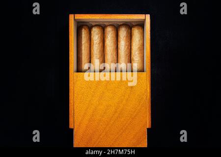 Boîte de cigares cubains sur une table noire dans l'obscurité.Des cigares haut de gamme chers en cadeau. Banque D'Images