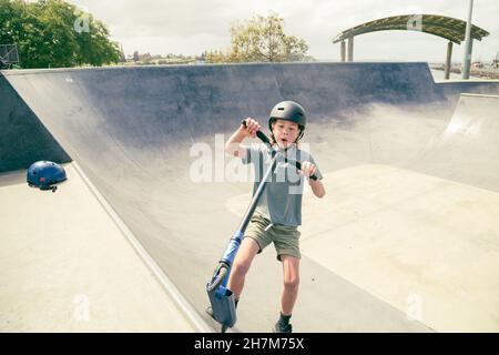 Portland, Victoria Australie- 14 novembre 2021- enfants qui voyagent en scooter au parc de skate local par temps nuageux Banque D'Images