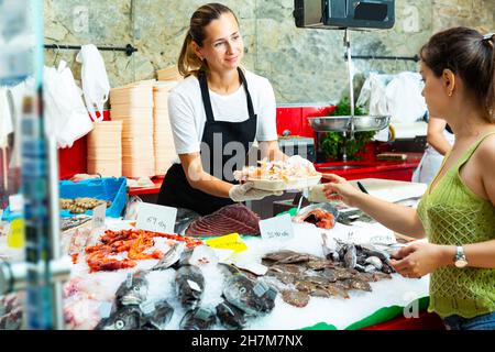 travailleur de la boutique de poissons offrant des langoustines fraîches et brutes au client Banque D'Images