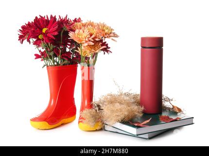 Bottes en caoutchouc avec fleurs, thermos et livres sur fond blanc Banque D'Images