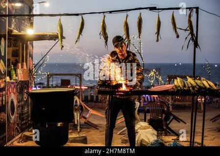 Gaza, Palestine.23 novembre 2021.Un vendeur de rue palestinien a grillé du maïs sur une plage de Gaza pendant le coucher du soleil.Crédit : SOPA Images Limited/Alamy Live News Banque D'Images