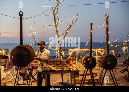 Gaza, Palestine.23 novembre 2021.Un vendeur de rue palestinien a grillé du maïs sur une plage de Gaza pendant le coucher du soleil.Crédit : SOPA Images Limited/Alamy Live News Banque D'Images