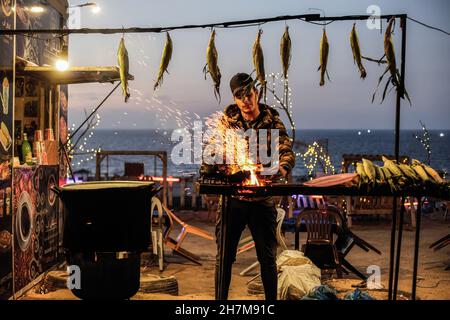 Gaza, Palestine.23 novembre 2021.Un vendeur de rue palestinien a grillé du maïs sur une plage de Gaza pendant le coucher du soleil.(Photo de Mahmoud Issa/SOPA Images/Sipa USA) crédit: SIPA USA/Alay Live News Banque D'Images