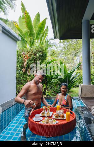 petit déjeuner flottant dans la piscine, thé l'après-midi ou petit déjeuner flottant dans la piscine. homme et femme prenant le petit déjeuner dans la piscine Banque D'Images