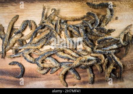 Petit poisson de vendace frits et battus (Coregonus albula) sur un panneau en bois Banque D'Images