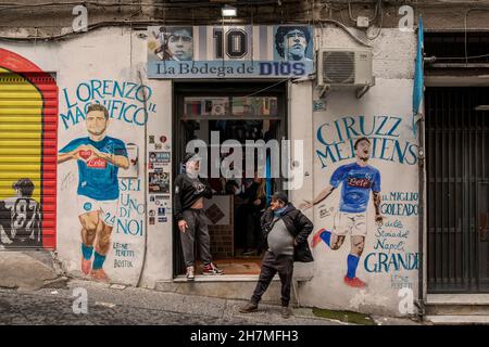 Neapel, Italie.23 novembre 2021.Des hommes se tiennent devant l'entrée d'un pub nommé d'après la légende du football Maradona dans les quartiers espagnols.Un an après la mort de la star du football dans une résidence privée au nord de Buenos Aires, Maradona est commémoré avec des hommages, des séries télévisées et des mémoriaux - y compris à Naples, où le 'Golden boy' a joué pendant des années à SSC Napoli.(À dpa 'Un an sans Diego: Hommages et accusations à l'anniversaire de la mort de Maradona') Credit: Alessio Paduano/dpa/Alay Live News Banque D'Images