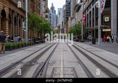 Vue sur la rue des voies ferrées du tram dans le quartier central des affaires de George Street, Sydney, Australie, le 20 novembre 2021.Route, personnes et bâtiments. Banque D'Images