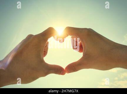 Photo tonifiée des mains en forme de coeur sur fond de ciel Banque D'Images