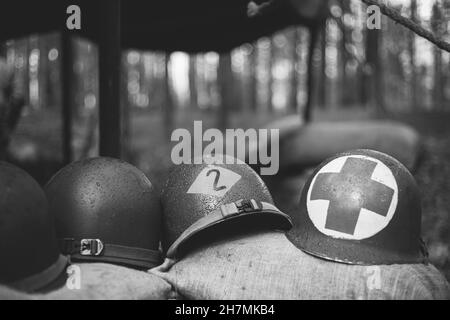 Casques métalliques du soldat d'infanterie de l'armée des États-Unis à la Seconde Guerre mondiale Casques près de la tente de camping dans Forest Camp. Photographie en noir et blanc. Banque D'Images