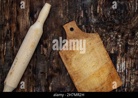 Rouleau et planche à découper en bois sur une surface en bois sombre brûlé.Ustensiles de cuisine.Vue de dessus.Mise au point sélective. Banque D'Images