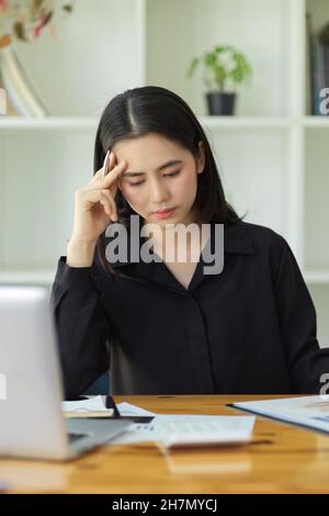 Portrait d'une femme gestionnaire réfléchie stressée en raison du travail excessif sur son lieu de travail au bureau. Banque D'Images