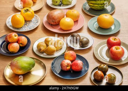 Ensemble d'assiettes fourrées de fruits assortis avec pommes rouges, tomates kumato, avocats, poires, pamplemousses et mangues Banque D'Images