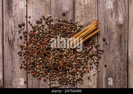 Vue de dessus avec des graines de poivre multicolores, des bâtonnets de cannelle et des graines d'anis étoilé sur une table en bois Banque D'Images