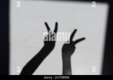 Ombre des mains de femmes sur un mur en béton, les mains montrent le signe de victorin Banque D'Images