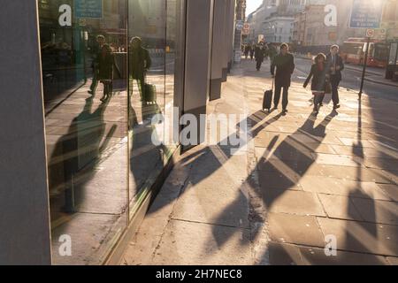 Des piétons traversent la lumière solaire d'automne réfléchie sur Moorgate dans la City de Londres, le quartier financier de la capitale, le 23 novembre 2021, à Londres, en Angleterre. Banque D'Images
