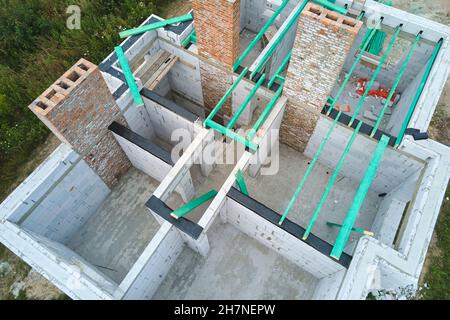 Vue aérienne du cadre inachevé de la maison privée avec murs en béton léger aéré et poutres de toit en bois en construction. Banque D'Images