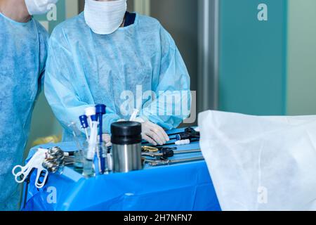 Mains de chirurgiens portant des gants chirurgicaux et des instruments chirurgicaux stériles pour la chirurgie laparoscopique sur une table bleue dans la salle d'opération.Mise au point sélective. Banque D'Images