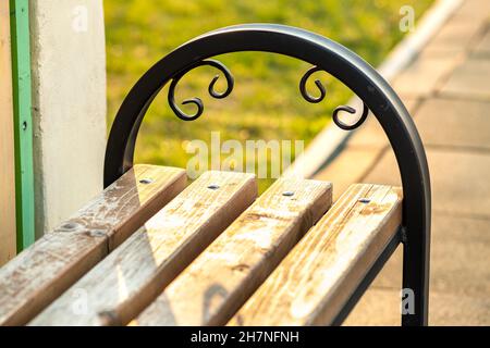 Gros plan de banc de parc en bois avec poignée en métal à l'extérieur. Banque D'Images