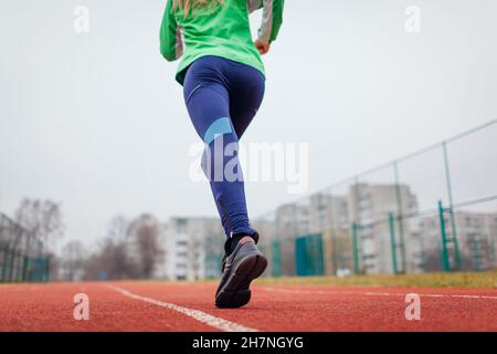 Jeune athlète de course sur le terrain de sport en automne.Gros plan sur les baskets et les jambes des femmes.Un mode de vie actif et sain Banque D'Images
