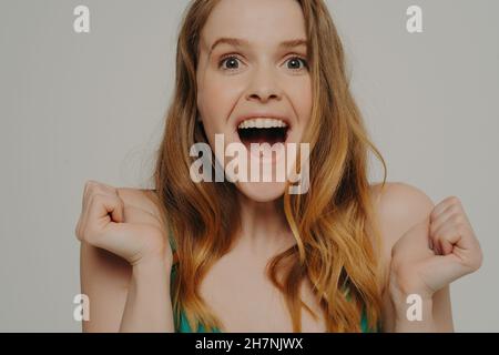 Surprise surprise surprise jeune femme clamant des coupes et hurlant de l'excitation, isolé sur gris Banque D'Images