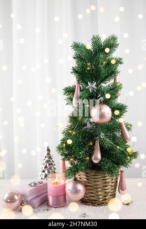 Décoration moderne en boules de couleur rose pastel accrochée à l'arbre de Noël dans le salon de la maison, avec cadeaux roses et bougie.CHRI de style rose pastel Banque D'Images