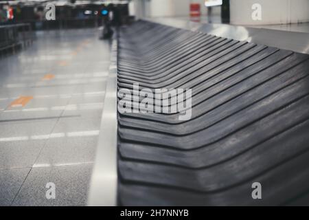 Une zone de récupération des bagages dans un hall d'une zone d'arrivée d'aéroport avec un tapis roulant vide en mouvement entouré de surfaces en chrome, avec une zone de copie sur Banque D'Images