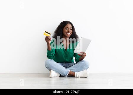 Bonne femme afro-américaine avec carte de crédit et tablette numérique Banque D'Images
