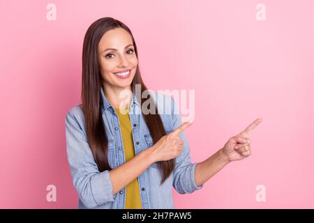 Photo de brunette fraîche femme mûre indiquer vide l'espace de porter Jean veste isolée sur fond rose pastel Banque D'Images