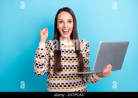 Photo d'une femme mature et confiante tenue habillée pull-over lecture moderne gadget levant poing isolé couleur bleu arrière-plan Banque D'Images