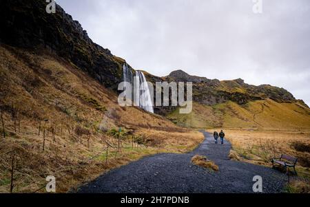 Touristes se tenant en face de Seljalandsfoss une des plus célèbres cascades dans le sud de l'Islande, la plus célèbre cascade islandaise Banque D'Images
