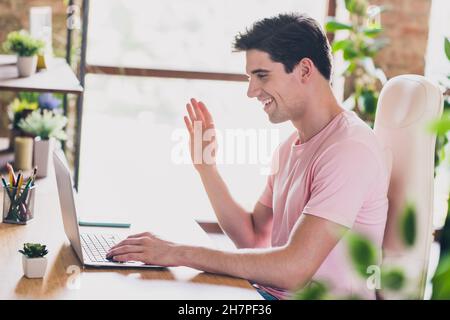 Profil vue latérale portrait d'un sympathique homme gai parlant sur la webcam travaillant à distance chat à la maison confortable à l'intérieur Banque D'Images