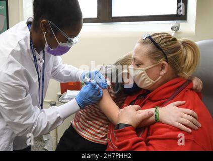 Racine, Wisconsin, États-Unis.24 novembre 2021.EMILY CHAFFEE, 8 ans, tient sa mère TRINA CHAFFEE comme JALEESA JENKIN R.N. lui donne son coup de feu alors que la ville de racine, Wisconsin tient une clinique vaccinale COVID‚-19 pour enfants„ au département de santé de la ville mercredi 24 septembre 2021, les écoles ont été fermées pour les vacances de Thanksgiving.Le Père Noël était sur place pour donner aux enfants des canes de bonbons, des crayons et des livres de coloriage après leur inoculation.Les adultes pourraient également être inoculés.Les résidents adultes et enfants de la ville qui ont reçu leurs premiers coups ont reçu des chèques-cadeaux de 50 $.(Credit image: © Mark Hertzber Banque D'Images