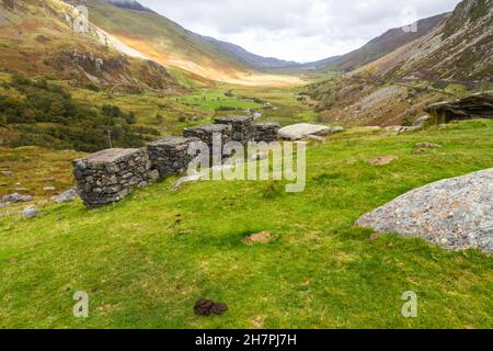 Vue depuis Ogwen Cottage sur le col de Nant Ffranson, blocs anti-chars de la Seconde Guerre mondiale en premier plan, éclairé au loin. Banque D'Images