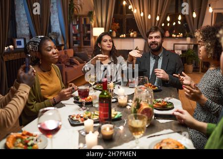 Groupe de jeunes jouant au jeu pendant un dîner à la table Banque D'Images