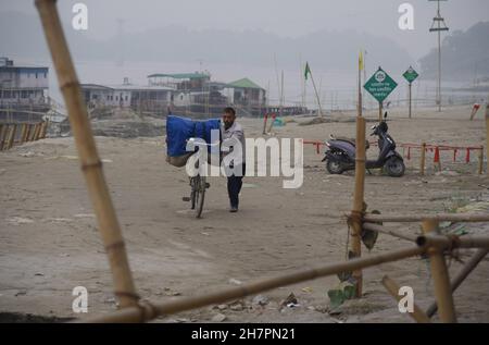 Guwahati, Guwahati, Inde.24 novembre 2021.Un laveur indien porte des vêtements dans un vélo après avoir lavé dans la rivière Brahmaputra à Guwahati Assam Inde le mercredi 24 novembre 2021 (Credit image: © Dasarath Deka/ZUMA Press Wire) Banque D'Images