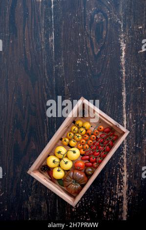 Boîte de tomates fraîches sur une table de cuisine rustique en bois Banque D'Images