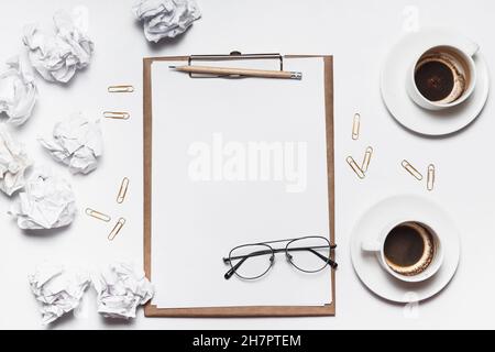 Des papiers froissés éparpillés, des tasses vides de café sur la table d'un travailleur de la création. Crise créative. Concept de stress, de troubles de santé mentale et de manque de moi Banque D'Images