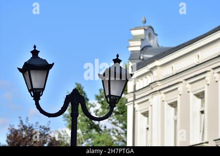 Une lampe antique contre un ciel bleu et debout à côté d'un bâtiment historique. Banque D'Images