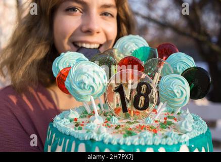 magnifique gâteau avec numéros 18, sucettes et guimauves sur des bâtons et un joyeux visage de la fille d'anniversaire. fête d'anniversaire amusante.Vacances, congra Banque D'Images