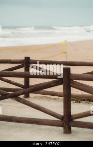 Un plan vertical avec une faible profondeur de champ d'une clôture en bois brun en bois rond sur la plage du soir avec les vagues de l'océan et l'eau dans un d Banque D'Images