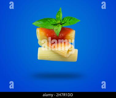 pâtes rigatoni à la sauce tomate flottant sur fond bleu Banque D'Images