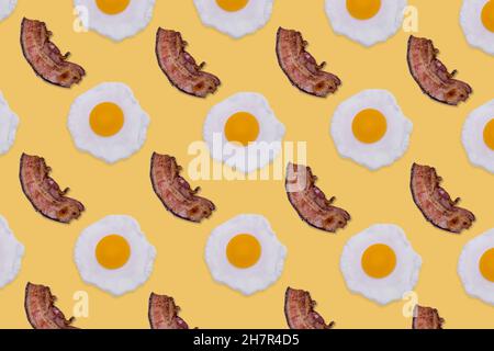 Modèle alimentaire créatif composé d'œufs frits et de tranches de bacon croustillant sur fond jaune vif.Concept petit déjeuner minimal.Vue de dessus.Pose à plat. Banque D'Images