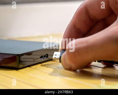 Disque dur USB de type 3.0, homme insérant un câble dans un disque dur externe portable, détail de l'objet, main très gros plan.Données numériques, stockage multimédia personnel Banque D'Images