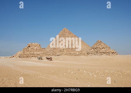 Chariots tirés par des chevaux près des pyramides de Gizeh.Les pyramides de Menkaure et de Queens sont vues depuis le désert Banque D'Images
